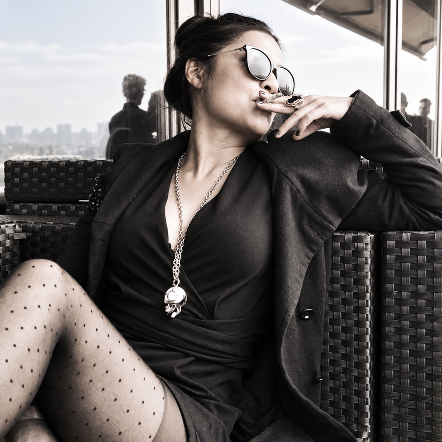 Natalie seated in sunglasses and a dark jacket, in a black-and-white portrait.