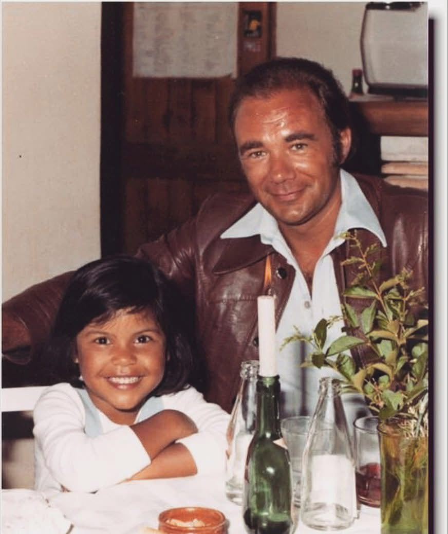 A childhood family photograph of Natalie smiling beside her father.